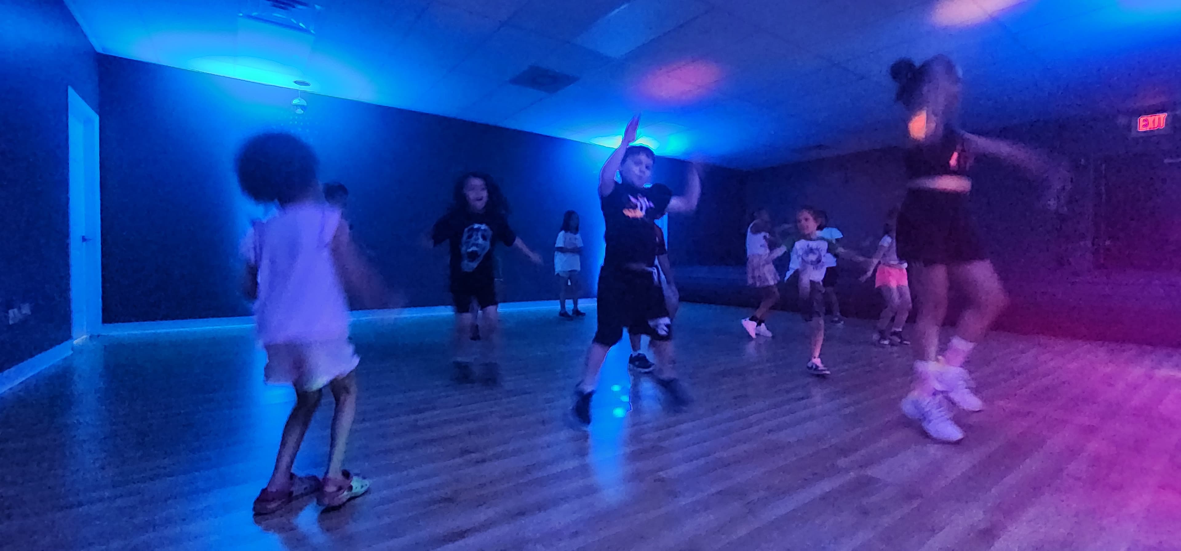 Children dancing together under blue lights in the indoor movement room