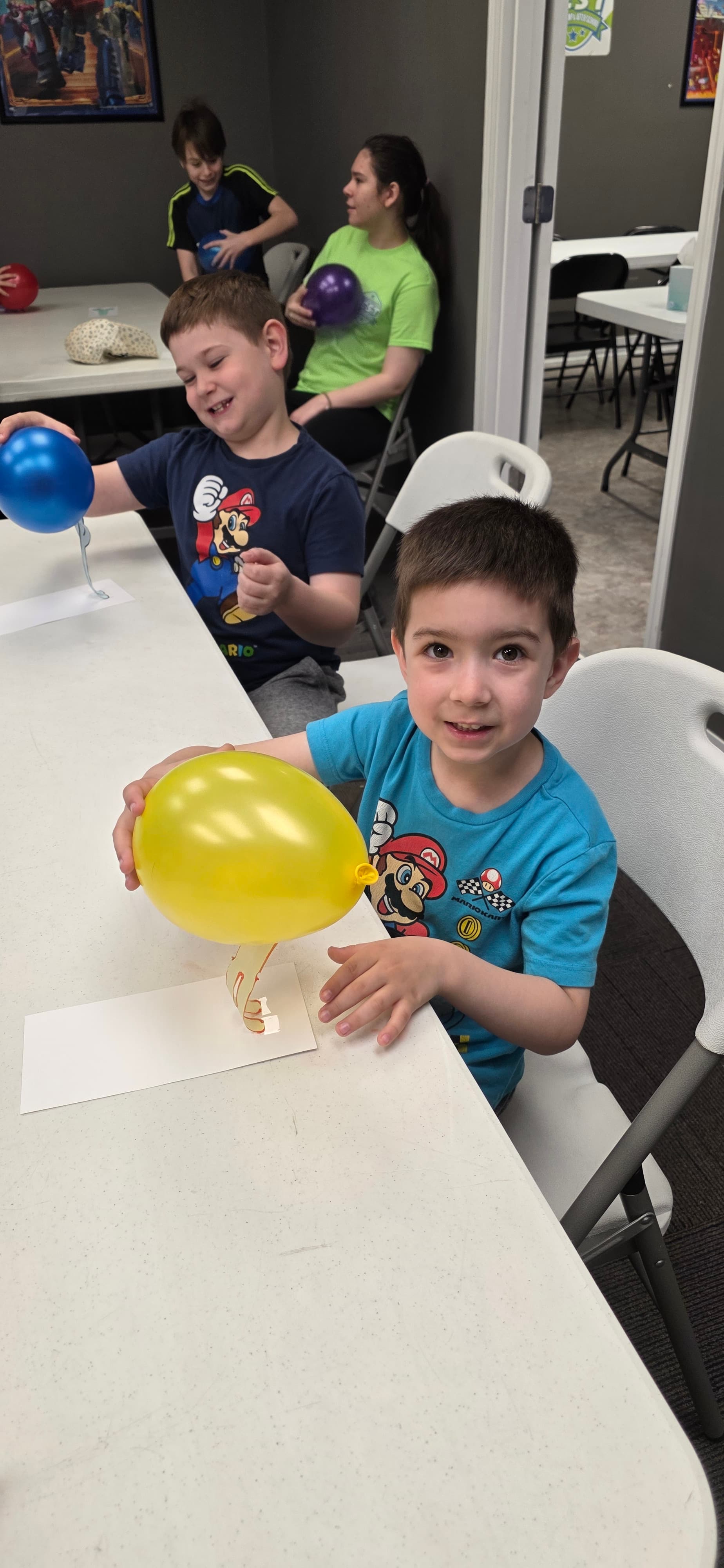 Children playing a balloon game together at an activity table