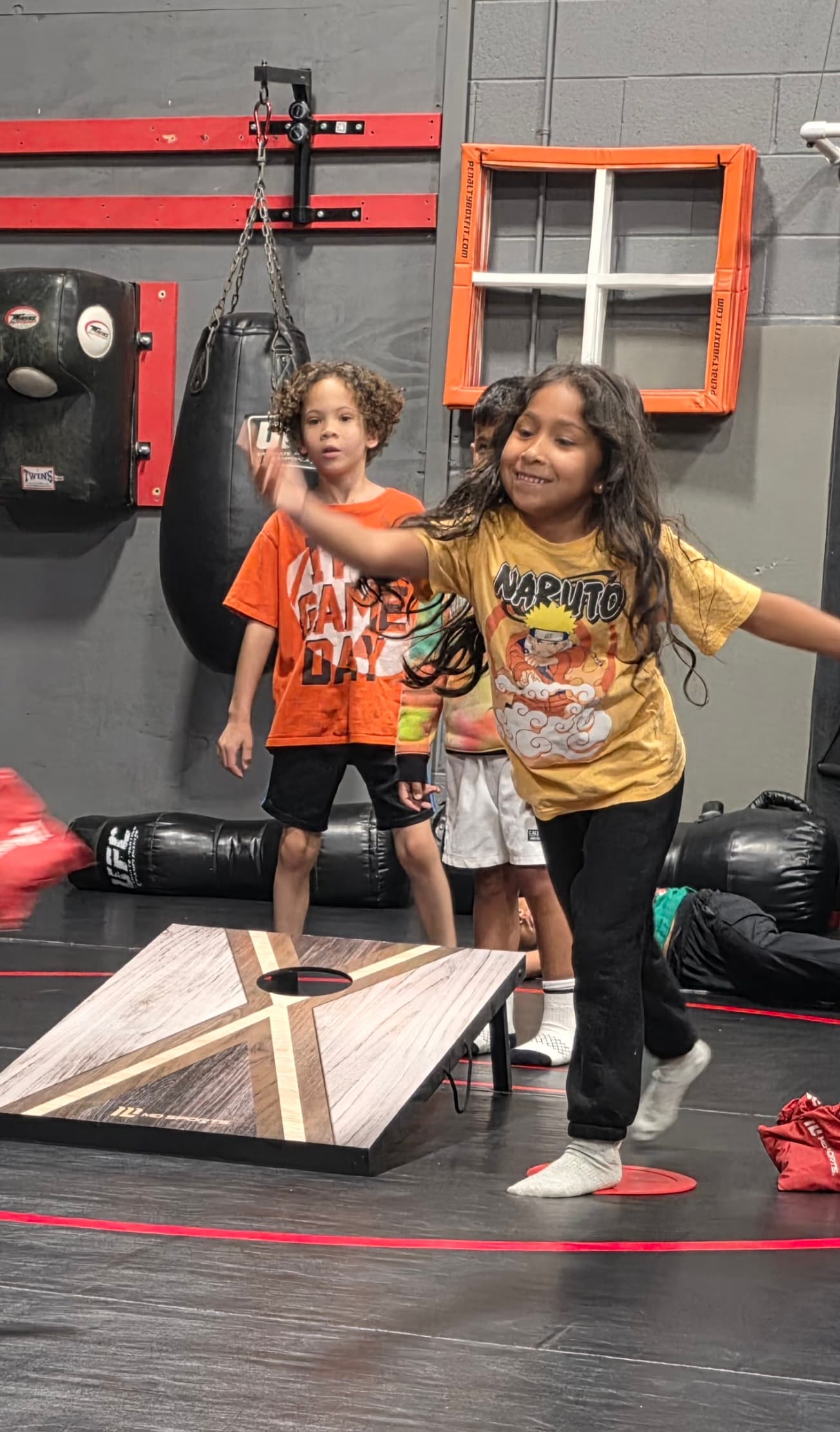 Child taking a turn at a beanbag toss game in the indoor training area